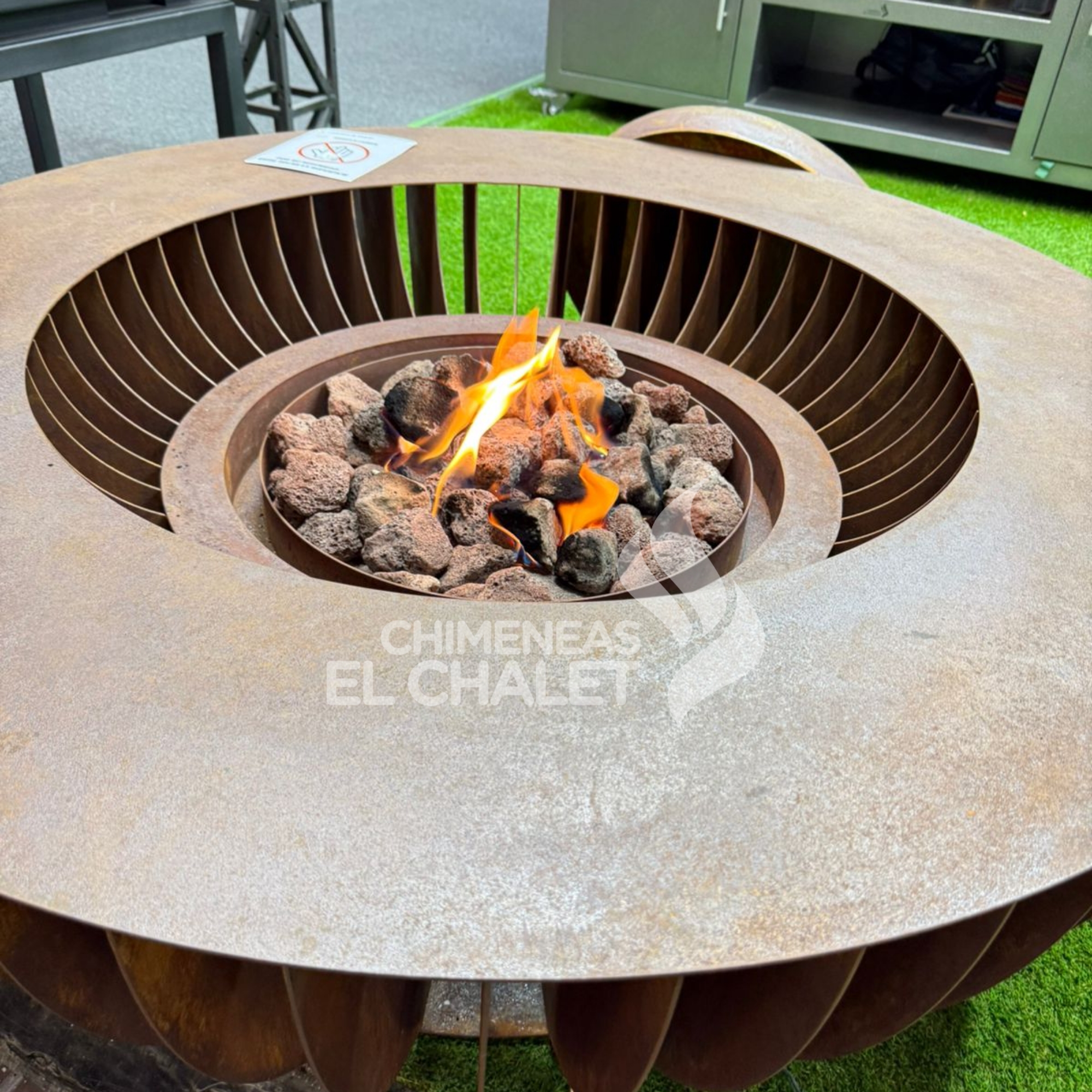 Brasero moderno con fuego vivo y piedras volcánicas.